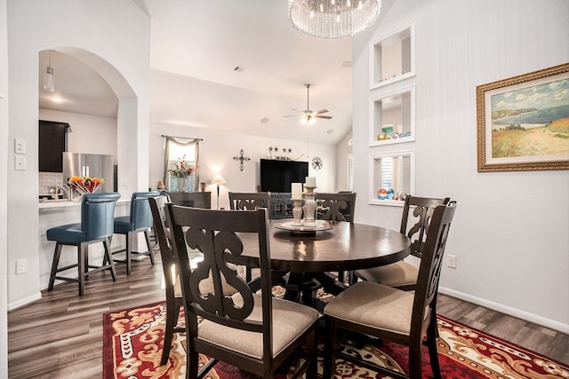 dining area with lofted ceiling, ceiling fan with notable chandelier, and dark hardwood / wood-style floors