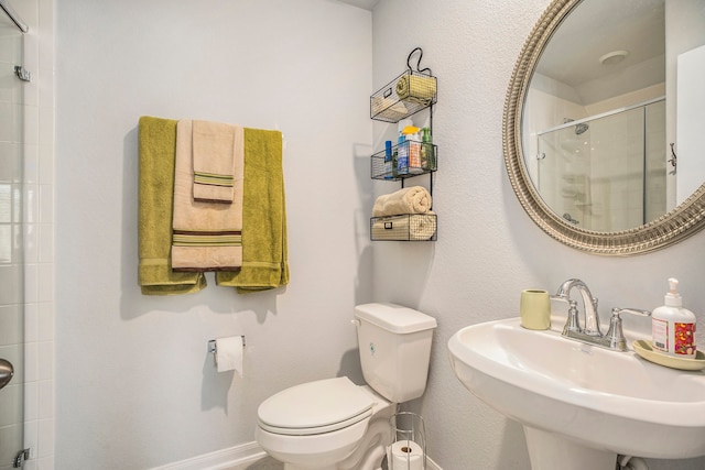 bathroom with toilet, a shower with shower door, and sink