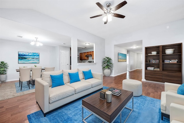 living room with ceiling fan with notable chandelier, vaulted ceiling, and hardwood / wood-style floors