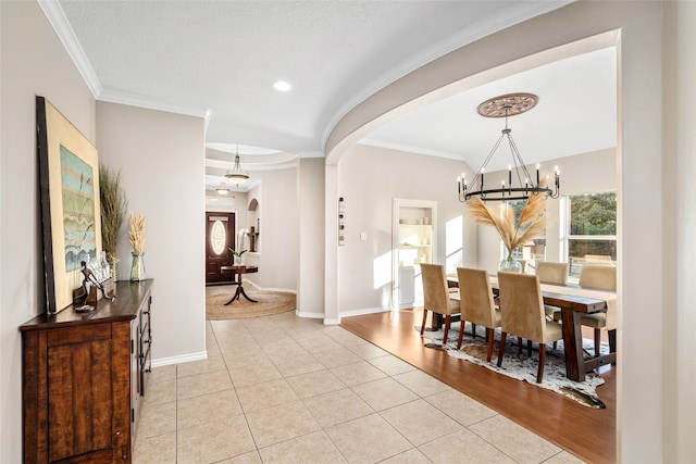 dining area with an inviting chandelier, light wood-type flooring, and crown molding