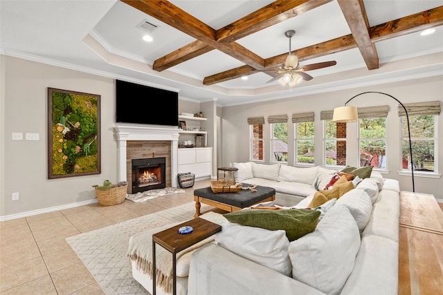 tiled living room featuring beamed ceiling, a tile fireplace, coffered ceiling, ornamental molding, and ceiling fan