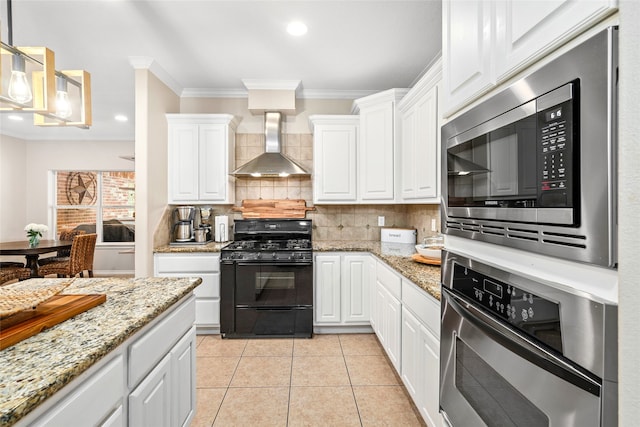 kitchen with appliances with stainless steel finishes, wall chimney exhaust hood, decorative backsplash, and white cabinetry