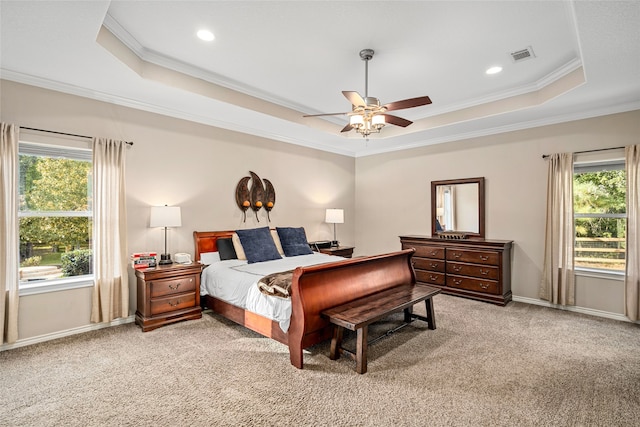 carpeted bedroom with ceiling fan, a raised ceiling, and crown molding