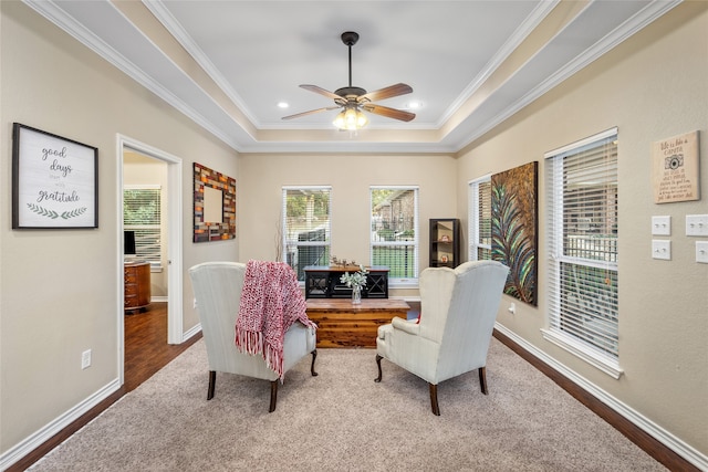 living area featuring ceiling fan, a tray ceiling, hardwood / wood-style floors, and ornamental molding