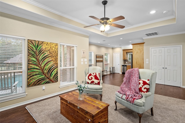 living room with a tray ceiling, ceiling fan, crown molding, and dark hardwood / wood-style flooring