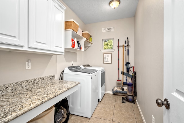 laundry area featuring cabinets, washer and dryer, a textured ceiling, and light tile patterned flooring