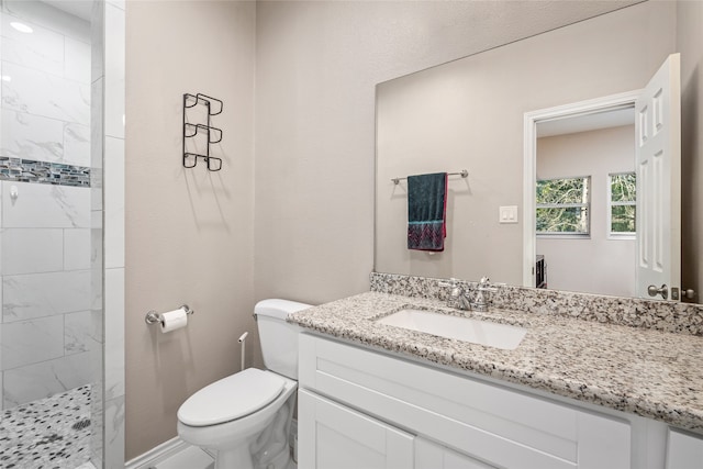 bathroom featuring tiled shower, vanity, and toilet