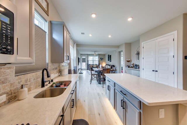 kitchen featuring sink, ceiling fan, gray cabinetry, a kitchen island, and light wood-type flooring