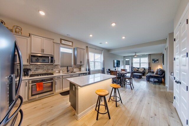 kitchen with stainless steel appliances, a kitchen island, a kitchen bar, and light hardwood / wood-style floors