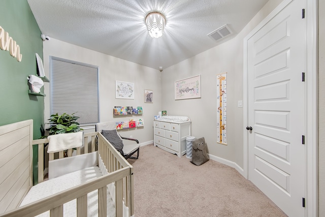 carpeted bedroom with a nursery area and a textured ceiling