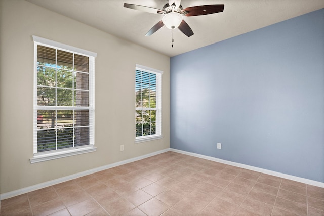 spare room with ceiling fan, a wealth of natural light, and light tile patterned flooring