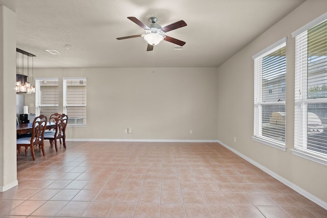 tiled empty room featuring ceiling fan with notable chandelier