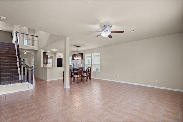 empty room with light tile patterned floors and ceiling fan with notable chandelier