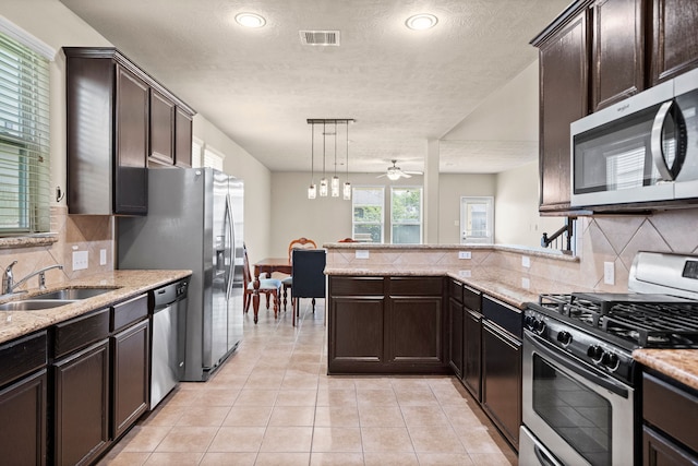 kitchen featuring sink, a textured ceiling, tasteful backsplash, decorative light fixtures, and stainless steel appliances