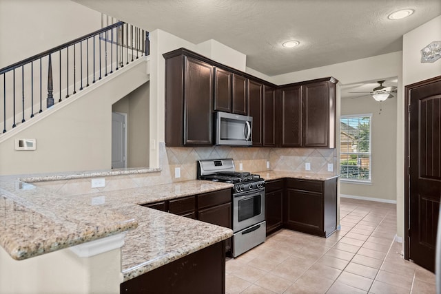 kitchen featuring kitchen peninsula, light stone counters, a textured ceiling, and appliances with stainless steel finishes