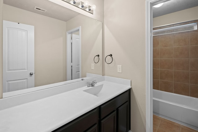 bathroom with tile patterned floors, vanity, and tiled shower / bath combo