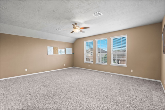 empty room with carpet, ceiling fan, lofted ceiling, and a textured ceiling