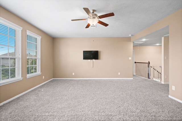 unfurnished room with carpet, ceiling fan, and a textured ceiling