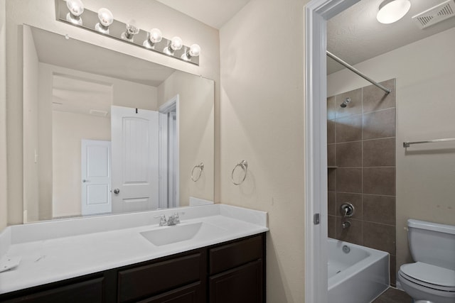 full bathroom featuring a textured ceiling, vanity, tiled shower / bath combo, and toilet