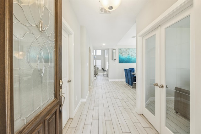 corridor with french doors and light hardwood / wood-style flooring