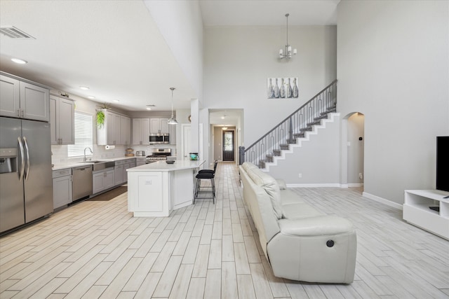 kitchen with gray cabinets, pendant lighting, stainless steel appliances, a kitchen bar, and a center island