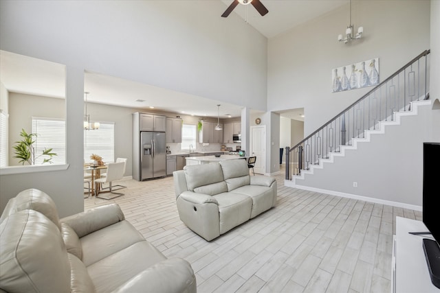 living room with sink, ceiling fan with notable chandelier, light hardwood / wood-style floors, and high vaulted ceiling