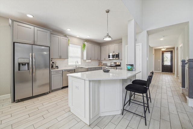 kitchen with stainless steel appliances, pendant lighting, gray cabinets, and a wealth of natural light