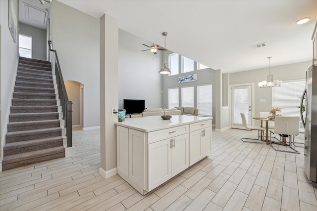 kitchen featuring white cabinets, ceiling fan with notable chandelier, pendant lighting, and light hardwood / wood-style floors