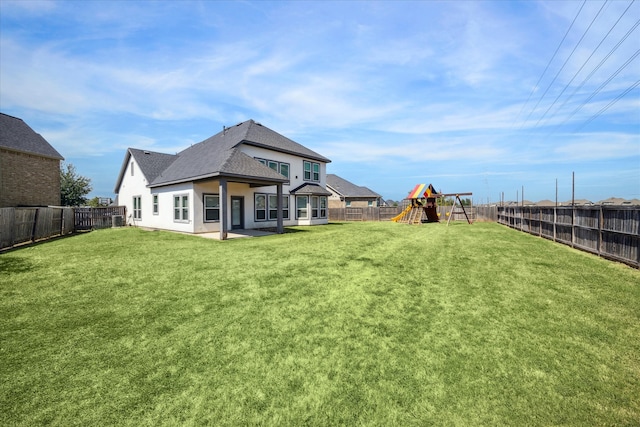 rear view of property with a playground, a yard, and a patio