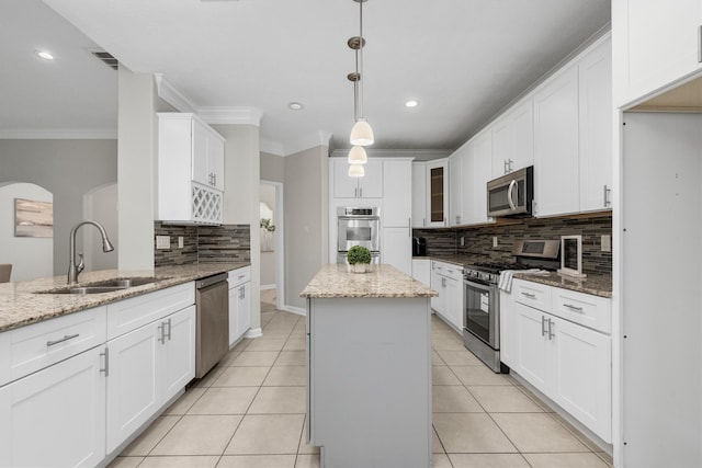 kitchen with appliances with stainless steel finishes, white cabinetry, light stone countertops, a center island, and sink