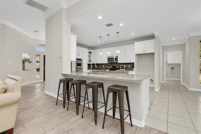 kitchen featuring a kitchen breakfast bar, hanging light fixtures, stainless steel appliances, and white cabinets