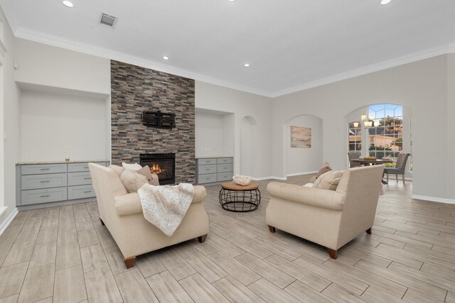 living room featuring a stone fireplace, light wood-type flooring, and crown molding