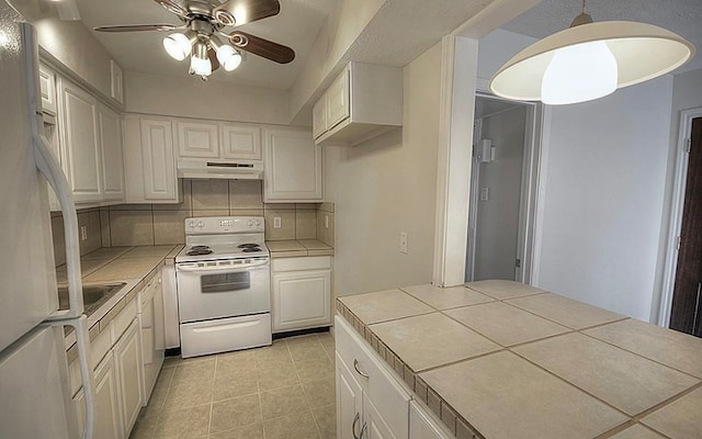 kitchen with pendant lighting, tile counters, white appliances, and decorative backsplash