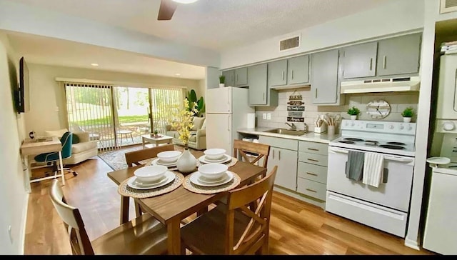 kitchen with light hardwood / wood-style floors, sink, backsplash, white appliances, and ceiling fan