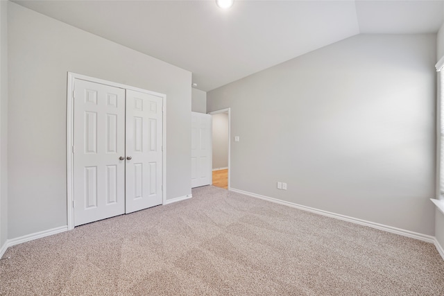 unfurnished bedroom featuring a closet, carpet flooring, and lofted ceiling