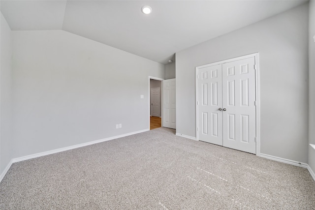 unfurnished bedroom featuring light colored carpet, a closet, and vaulted ceiling