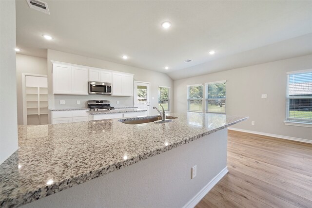 kitchen with white cabinetry, light hardwood / wood-style flooring, stainless steel appliances, and light stone counters