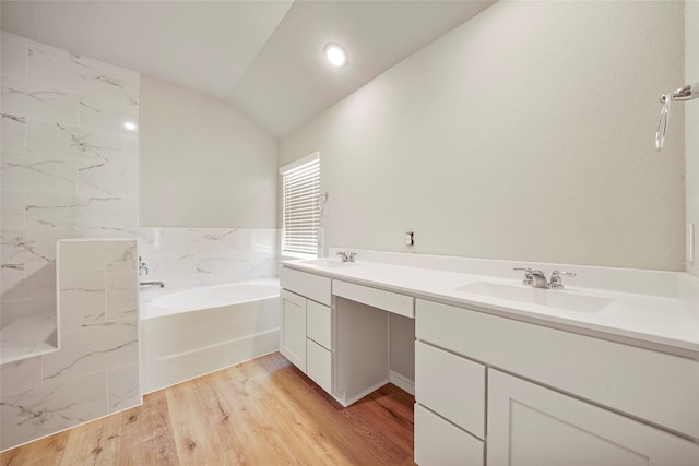 bathroom with vanity, hardwood / wood-style floors, vaulted ceiling, and a tub