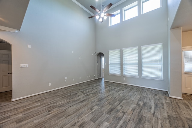 unfurnished living room with ceiling fan, ornamental molding, hardwood / wood-style floors, and a high ceiling