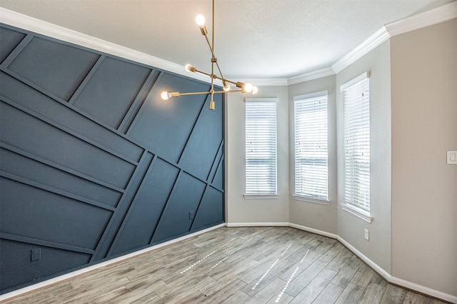 empty room featuring a notable chandelier, ornamental molding, light hardwood / wood-style flooring, and plenty of natural light