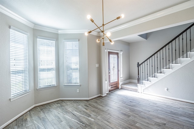 entrance foyer featuring wood-type flooring, ornamental molding, and a chandelier