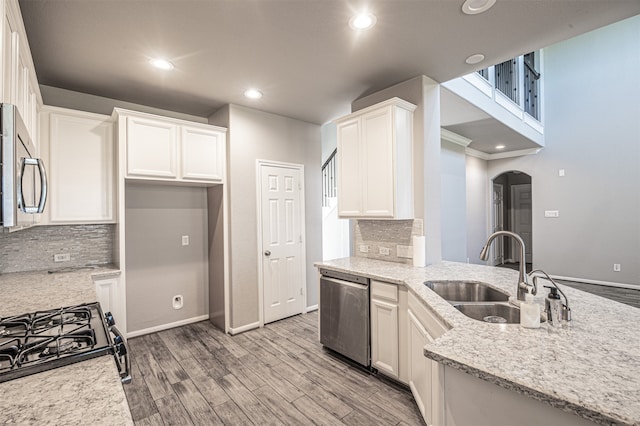 kitchen featuring white cabinets, sink, backsplash, stainless steel appliances, and light wood-type flooring