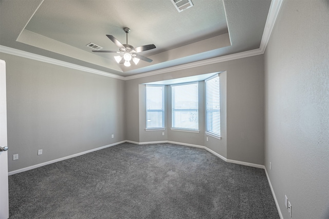 empty room featuring dark carpet, a tray ceiling, ceiling fan, and crown molding