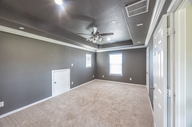 carpeted spare room with a textured ceiling, a raised ceiling, ornamental molding, and ceiling fan