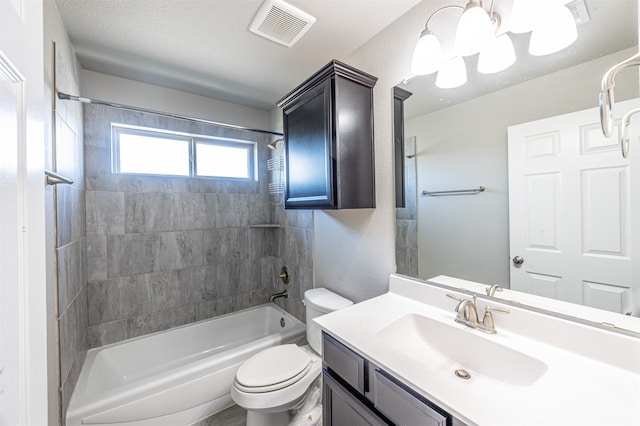 full bathroom with tiled shower / bath, vanity, toilet, and a textured ceiling