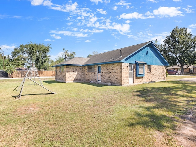 rear view of property with a playground and a yard