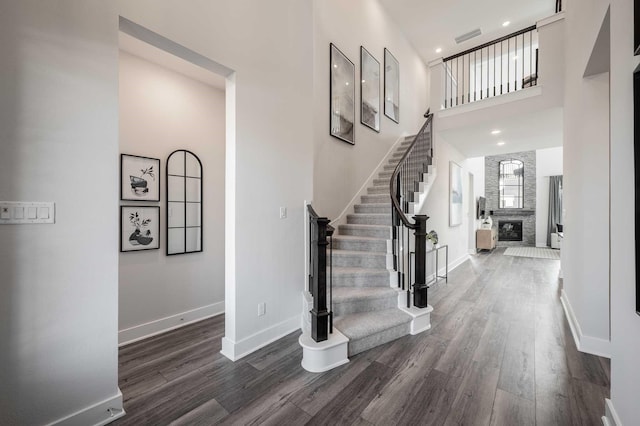 foyer featuring a large fireplace, dark hardwood / wood-style floors, and a high ceiling