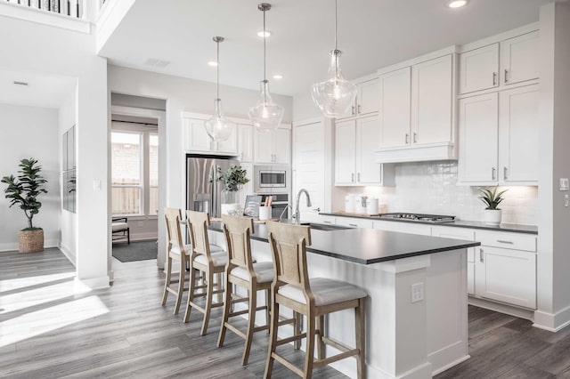 kitchen featuring sink, stainless steel appliances, white cabinets, and a center island with sink