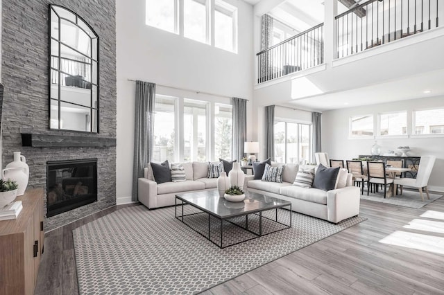 living room with a high ceiling, light hardwood / wood-style flooring, and a stone fireplace