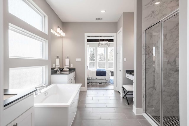 bathroom featuring tile patterned flooring, vanity, an inviting chandelier, and independent shower and bath